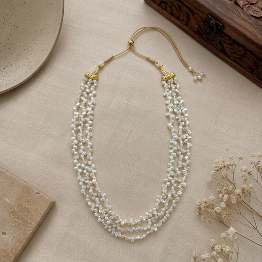 Flat lay of the Elara 3-Line Keshi Freshwater Pearl Necklace featuring three strands of natural keshi freshwater pearls with an adjustable dori for a bold Indo-western look.