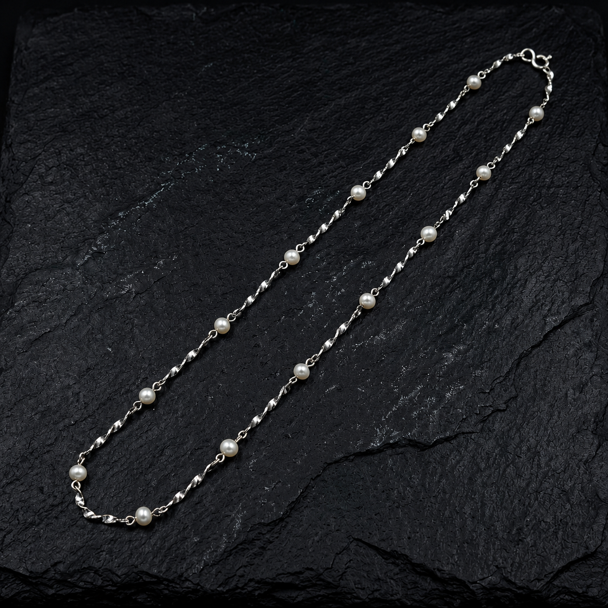 Flat lay of the Aurea 925 Sterling Silver Pearl Chain handcrafted with genuine freshwater pearls on a twisted sterling silver chain.